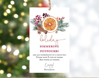 Puede incluir: Una etiqueta rectangular blanca con un diseño de acuarela de una rodaja de naranja, palitos de canela y vegetación. El texto dice "holiday simmering potpourri" con instrucciones y "Enjoy!" en la parte inferior.