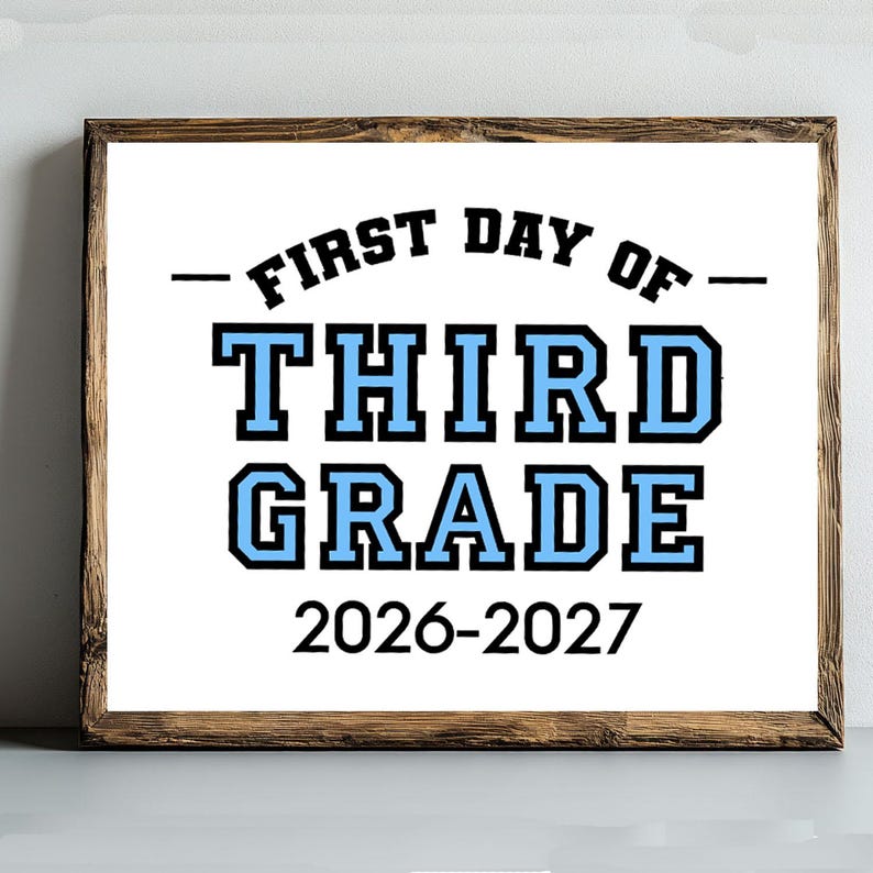 May include: A rectangular sign in a dark wood frame featuring the text FIRST DAY OF THIRD GRADE in black and light blue block lettering, with the school year 2026-2027 printed in black at the bottom against a white background.