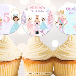 May include: Three round cupcake toppers featuring watercolor illustrations of nutcrackers, ballerinas, and a mouse king. The text reads Olivia's 5th birthday and Olivia is five. The designs include pink, blue, and purple hues with snowflakes.