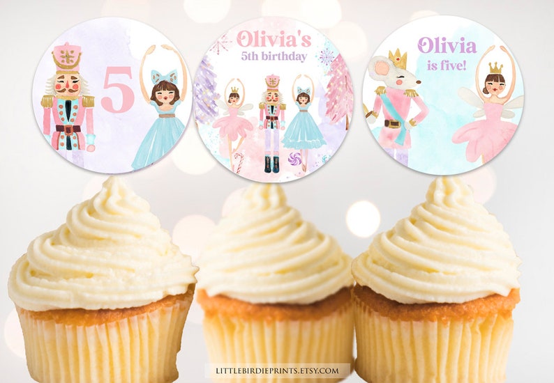 May include: Three round cupcake toppers featuring watercolor illustrations of nutcrackers, ballerinas, and a mouse king. The text reads Olivia's 5th birthday and Olivia is five. The designs include pink, blue, and purple hues with snowflakes.