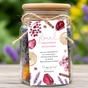 May include: A glass jar with a wooden lid, filled with dried lavender and other botanicals. A tag tied with twine reads "floral simmering potpourri" with instructions and the words "Happy spring!" and the name "Katie Jones".