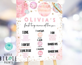 May include: A pink and gold space-themed first birthday chart for a baby girl named Olivia. The chart includes details about her weight, height, favorite foods, and activities. It features a watercolor background with planets and stars.