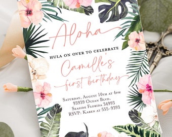 May include: A white invitation card with a tropical floral design. The card features the word "Aloha" in coral script, along with event details for Camille's first birthday. The design includes pink hibiscus flowers and green tropical leaves.