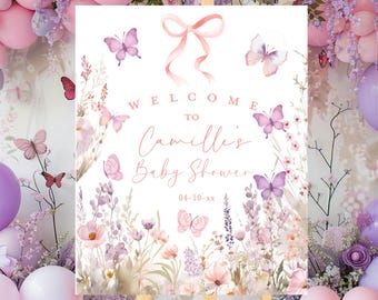 May include: A baby shower welcome sign on an easel. The sign features a floral design with butterflies and the text "Welcome to Camille's Baby Shower" in a delicate script. The color palette includes pinks, purples, and whites.