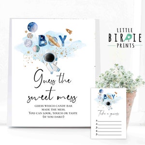 May include: A blue and gold astronaut themed baby shower game card with the text "Guess the sweet mess" and "Guess which candy bar made the mess. You can look, touch or taste (if you dare!)".