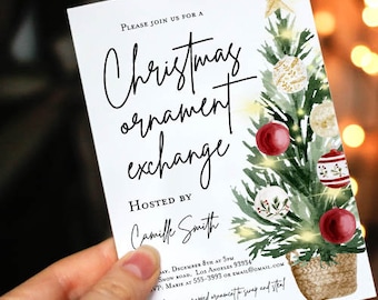 May include: A white invitation card for a Christmas ornament exchange, held by a hand. The card features a Christmas tree illustration with red and white ornaments. Text on the card reads "Christmas ornament exchange" and "Hosted by Camille Smith."