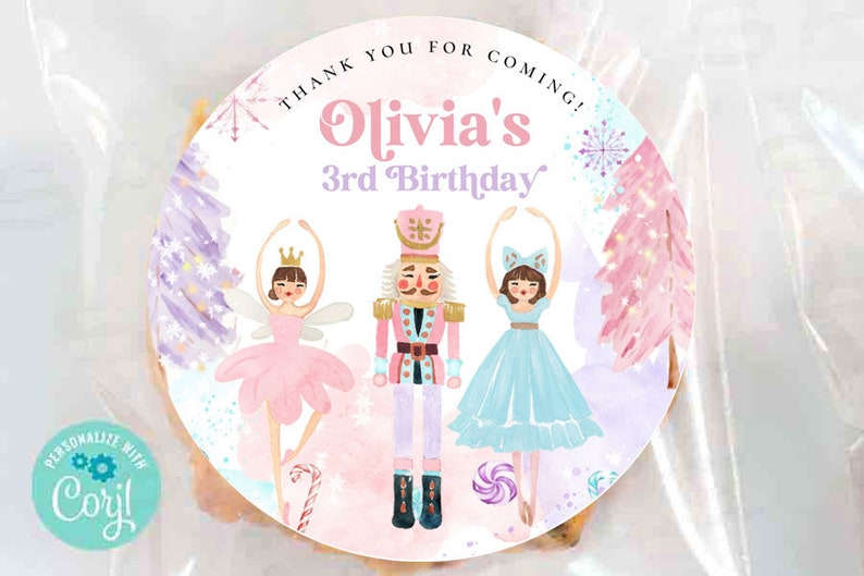 May include: A round sticker featuring a nutcracker flanked by two ballerinas in pink and blue dresses. The text reads "THANK YOU FOR COMING!" and "Olivia's 3rd Birthday". The design includes watercolor trees, snowflakes, and candy canes in soft pastel colors.