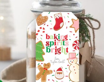 May include: A glass jar filled with baking ingredients, adorned with a tag featuring Christmas cookie illustrations and the words "baking spirits bright." The tag includes a gingerbread man, snowman, and Santa.