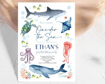May include: A blue and white invitation for a first birthday party with the theme "One-der the Sea". The invitation features a shark, a turtle, an octopus, a jellyfish, and a whale. The text on the invitation reads "It's a party One-der the Sea Join us to celebrate at Ethan's first birthday party Saturday, July 18th at 5pm 3939 West Palm Way, Ocean City Florida 33992 Bring a swimsuit RSVP. Carbon at 555-93939 by June 28th."