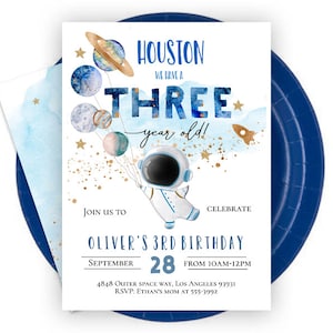 May include: Blue and gold astronaut birthday party invitation with a watercolor background. The invitation says "Houston, we have a three year old!" and includes the text "Join us to celebrate Oliver's 3rd Birthday, September 28, from 10am-12pm, 4848 Outer Space Way, Los Angeles 93931, RSVP: Ethan's Mom at 555-3992."