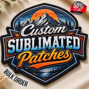 Op de afbeelding: Een op maat gemaakte gesublimeerde patch met een berg- en meerlandschap. De patch bevat de woorden "Custom Sublimated Patches" in een gestileerd lettertype. Het ontwerp omvat een zonsondergang, bomen en water. De patch is zwart met blauwe, oranje en witte accenten. De woorden "Bulk Order" zijn ook zichtbaar.