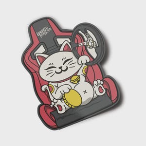 May include: A white cartoon cat sticker with a gold coin and a bell, seated in a red and black racing seat. The cat holds a steering wheel. The text "LOWERED LIFESTYLE" is visible.