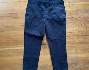 May include: A pair of navy blue dress pants. The pants have a button and zipper closure, belt loops, and pockets. The pants are made of a sturdy material and are suitable for various occasions.