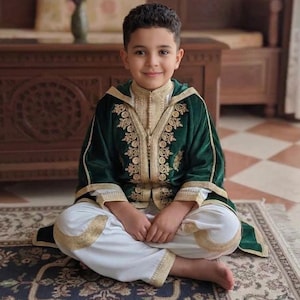 May include: A white ceramic mug with a black handle and the text "But First, Coffee" in a handwritten style. The mug is on a white surface. The mug is approximately 4 inches tall.