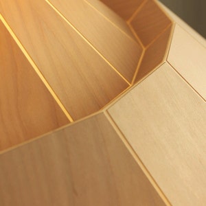 May include: A close-up of a wooden lampshade with a geometric design. The lampshade is made of light-colored wood and has a smooth, polished finish.