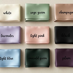 May include: Nine folded satin ribbons in various colors, including white, sage green, champagne, lavender, light pink, black, light blue, emerald green, and plum. Each ribbon displays its color name in a handwritten font.