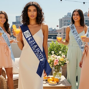 May include: A white ceramic mug with a black handle and the text "But First, Coffee" in a bold, black font. The mug is set against a blurred background, suggesting a cozy setting.