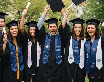 May include: A group of graduates in black gowns and mortarboards celebrating. They are holding diplomas and throwing their caps in the air. Some wear blue and white stoles with text like "Class of 2025" and "Nursing". Confetti is falling.