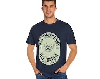 May include: Navy blue t-shirt with a humorous graphic. The graphic features a bulldog with a hockey stick inside an oval frame, accompanied by the text "YOUR MAKEUP LOOKS LIKE SOMEONE FARTED ON YOUR FACE."