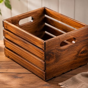 May include: A wooden storage crate with a dark brown stain. The crate has a slatted design and cut-out handles. The wood grain is visible. The crate is suitable for storage and measures approximately 30cm x 30cm x 20cm.