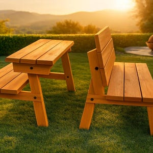 May include: A wooden picnic table and bench set. The set is made of light brown wood and is placed on a green lawn. The table has a built-in bench on one side. The bench has a backrest. The background features a hedge and a sunset.
