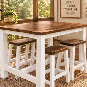 May include: A rectangular dining table with a dark brown wood grain top and a white painted wooden frame, accompanied by three matching stools featuring dark brown wood grain seats and white painted wooden legs, arranged on a woven rug.