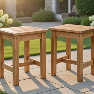 Könnte beinhalten: Zwei quadratische Beistelltische aus Holz mit natürlichem Finish. Die Tische haben eine Lamellenplatte und werden von vier stabilen Beinen mit Kreuzstützen getragen. Die Tische stehen auf einer Steinterrasse, mit Grün im Hintergrund.