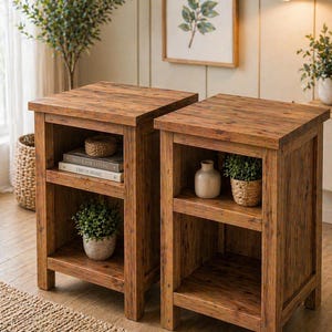 Può includere: Due comodini rustici in legno con finitura marrone caldo. Ogni tavolo ha due ripiani, con oggetti decorativi come piante e libri. I tavoli sono posizionati su un tappeto tessuto, creando un'atmosfera accogliente. I tavoli sono alti 61 cm.