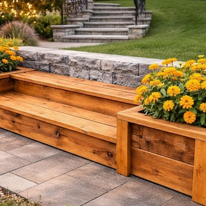 Puede incluir: Un banco de madera con jardineras integradas llenas de vibrantes flores amarillas. El banco es de madera marrón claro y está sobre un patio de piedra. La escena es al aire libre, con vegetación y un muro de piedra al fondo.