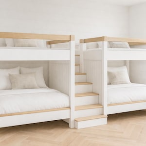 May include: Two white bunk beds with light wood accents. Each bed has a top and bottom bunk with white bedding and pillows. A staircase provides access to the top bunk. The beds are in a bright, airy room.