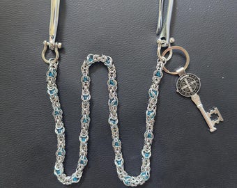 May include: A silver chain wallet chain with a blue beaded design. The chain has two silver clasps, one at each end. A key with a round pendant and a keyhole design hangs from one end.