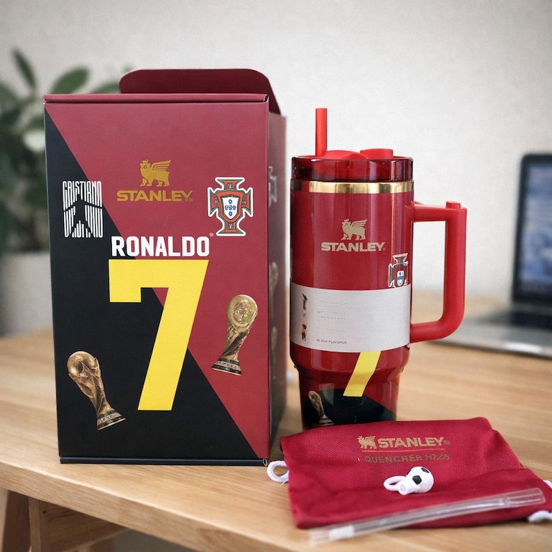 Pu&ograve; includere: Un bicchiere Stanley Quencher H2.0 rosso con bordo, manico e cannuccia dorati, caratterizzato da una grafica Ronaldo 7. &Egrave; esposto accanto alla sua scatola rossa abbinata con dettagli dorati, una sacca rossa con coulisse e un piccolo ciondolo a pallone.