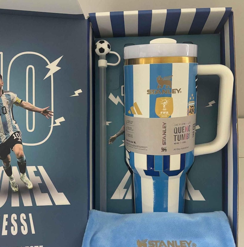 Pu&ograve; includere: Un bicchiere Stanley Quencher da 40 oz con strisce verticali blu e bianche, bordo dorato e manico bianco. Il bicchiere include una cannuccia con un topper a forma di pallone da calcio, in una scatola con un calciatore e il testo Lionel Messi.