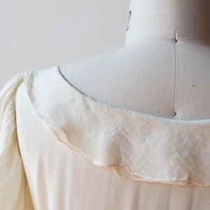 May include: A white vintage dress with a ruffled neckline and puffed sleeves.
