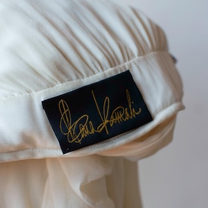 May include: A white garment with a black label that says "Carla Falini" in gold lettering.