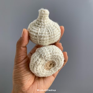 May include: A crocheted garlic bulb with a separate crocheted clove. The garlic is white and the clove is a light brown colour.