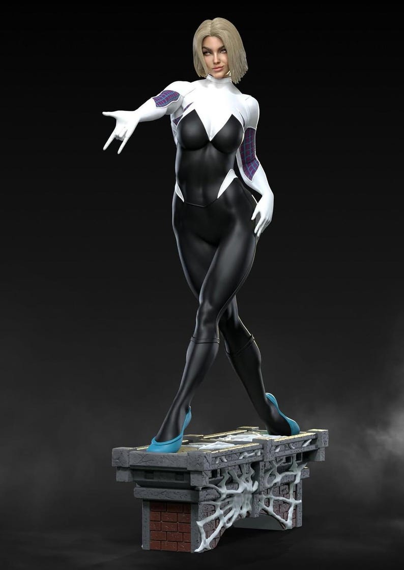May include: A statue of a female superhero in a black and white bodysuit with a spider-web design. The figure has blonde hair and is wearing blue heels. The statue is standing on a stone platform with a brick base.