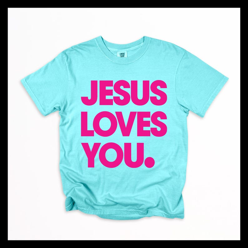 K&ouml;nnte beinhalten: Hellblaues T-Shirt mit dem Text "JESUS LOVES YOU." in leuchtend pinkfarbenen Gro&szlig;buchstaben. Das T-Shirt mit Rundhalsausschnitt ist aus weichem Stoff. Der Text ist mittig auf der Vorderseite des Kleidungsst&uuml;cks platziert.