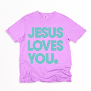 K&ouml;nnte beinhalten: Ein lilafarbenes T-Shirt mit dem Text "JESUS LOVES YOU" in gro&szlig;en, t&uuml;rkisfarbenen Buchstaben. Das Shirt hat einen Rundhalsausschnitt und kurze &Auml;rmel. Der Text ist mittig auf der Vorderseite des Shirts platziert.