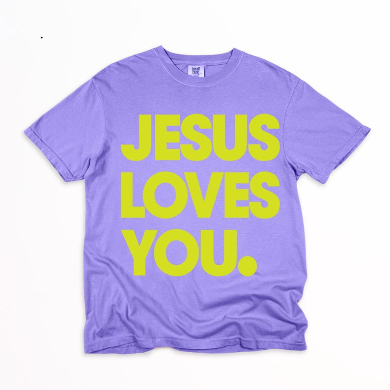 K&ouml;nnte beinhalten: Ein lilafarbenes T-Shirt mit dem Text "JESUS LOVES YOU" in leuchtendem Gelb. Das Shirt hat kurze &Auml;rmel und einen Rundhalsausschnitt und ist aus weichem Material gefertigt. Der Text ist mittig auf der Vorderseite platziert.