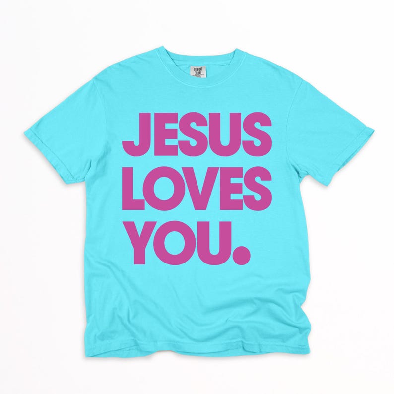 K&ouml;nnte beinhalten: Ein t&uuml;rkisfarbenes T-Shirt mit dem Aufdruck "JESUS LOVES YOU." in kr&auml;ftigen, pinkfarbenen Buchstaben. Der Text ist mittig auf der Vorderseite platziert. Das Shirt hat einen Rundhalsausschnitt und kurze &Auml;rmel.