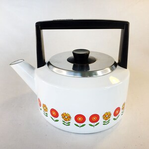 May include: White enamel teapot with a black handle and a silver lid. The teapot features a floral design with orange and yellow flowers.