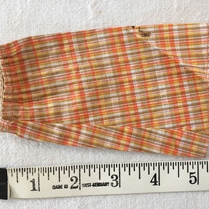 May include: A brown, orange, and white plaid fabric skirt with a hem that is approximately 5 inches long.