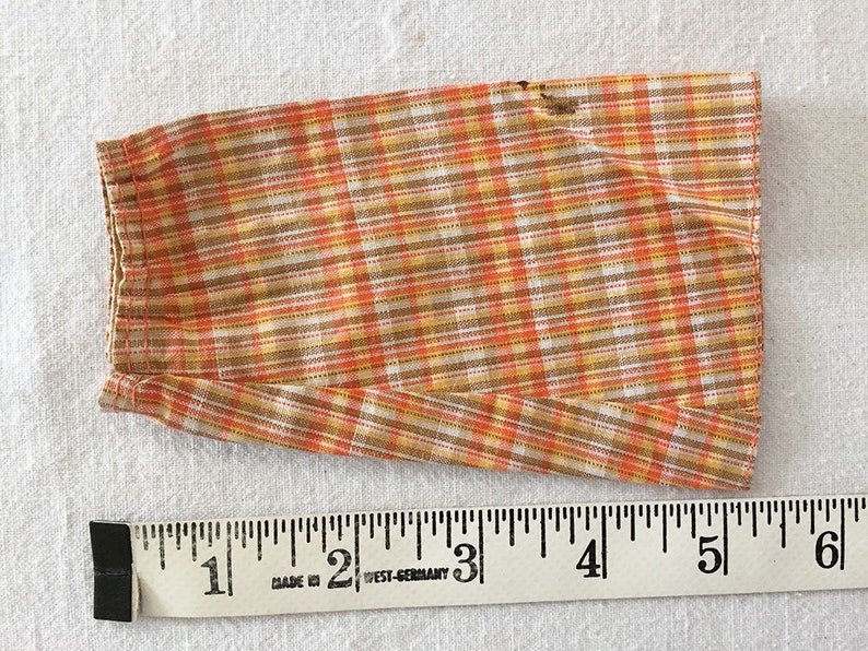 May include: A brown, orange, and white plaid fabric skirt with a hem that is approximately 5 inches long.