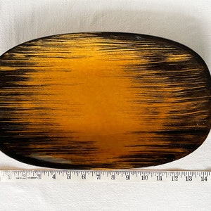May include: An oval-shaped serving tray with a black and gold striped pattern. The tray is approximately 15 inches long.