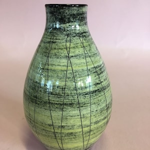 May include: A ceramic vase with a rounded body and a narrow neck. The vase features a green and black speckled pattern with vertical black lines. The interior and rim are black. The vase is a decorative item.