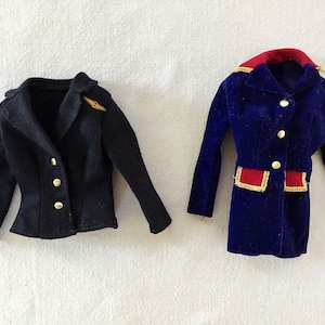 May include: Two doll-sized jackets, one black and one blue velvet with gold trim and red accents.