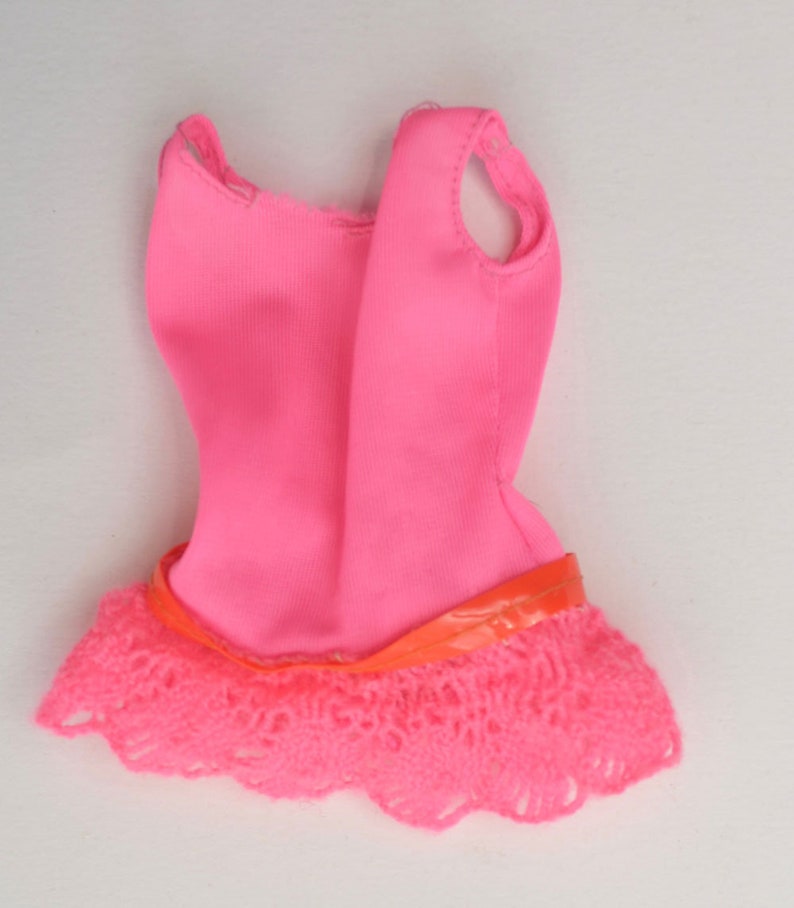 May include: A pink sleeveless leotard with a lace trim and a pink ribbon around the waist.