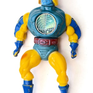 Puede incluir: Una figura de acción azul y amarilla con una pantalla de radar en el pecho. La figura tiene un casco amarillo y un cuerpo azul y amarillo.