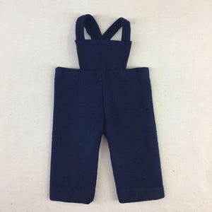 May include: A pair of dark blue overalls with a wide, crossed strap design. The overalls are made of a soft, textured fabric.